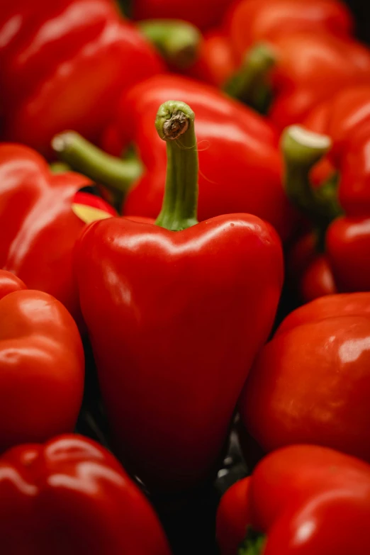 a pile of red peppers with green stems