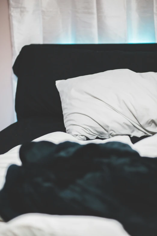 an unmade bed with black sheets and pillows