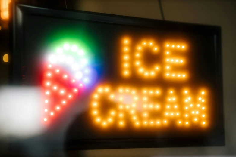 a colorful sign reading ice cream sits next to a light bulb