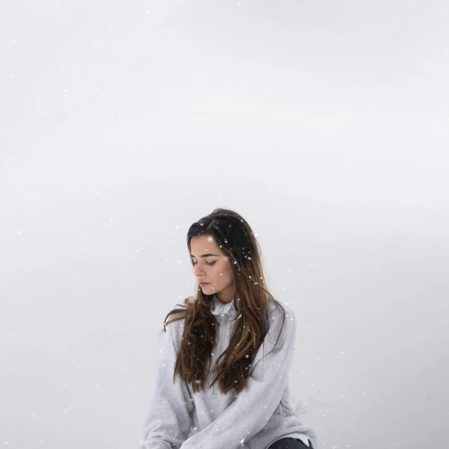 a girl is sitting outside in the snow