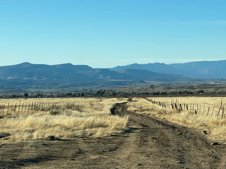 a dirt road runs down a grassy plains