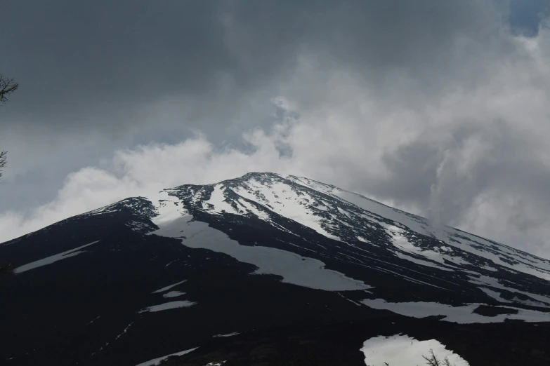 a snowy mountain has some clouds flying through it