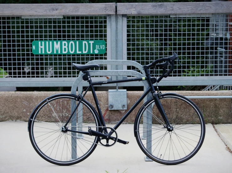 a black bicycle is shown in front of a fence