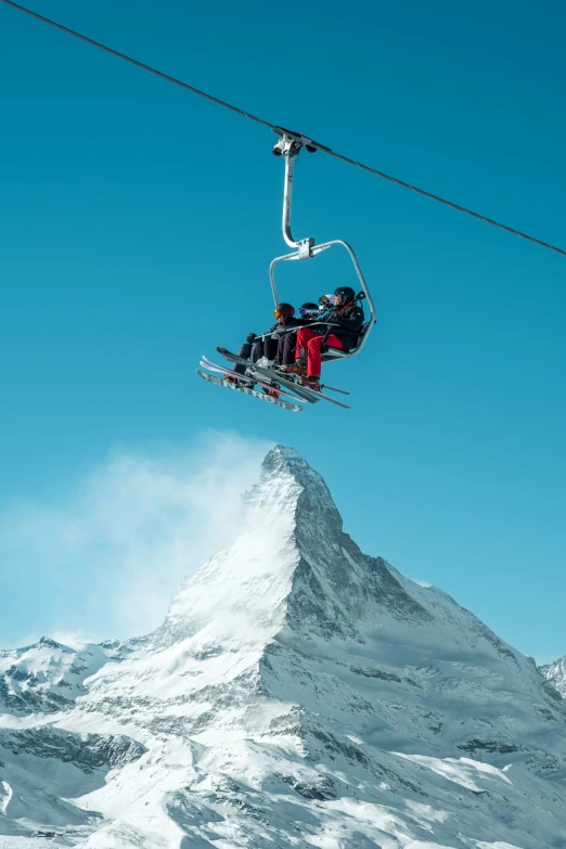 a group of people ride the ski lift with the mountain behind them