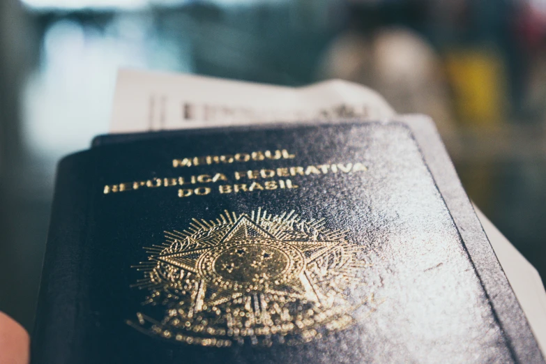 a close up of a person holding up a black passport