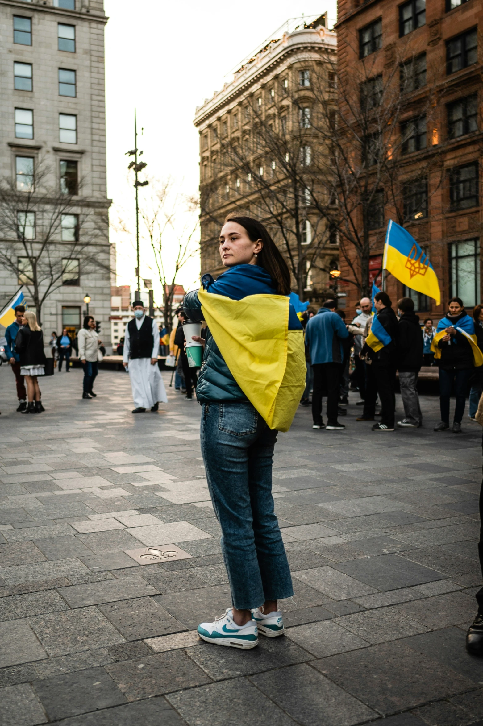 a woman standing in a city holding onto a flag