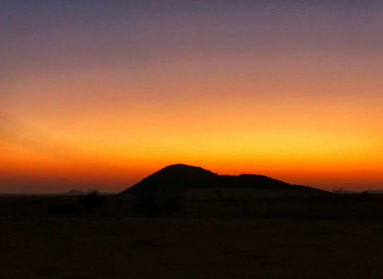 the silhouette of a desert plain against a sunset sky