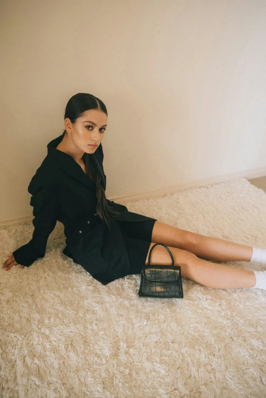 a woman sitting on the floor with a hand bag