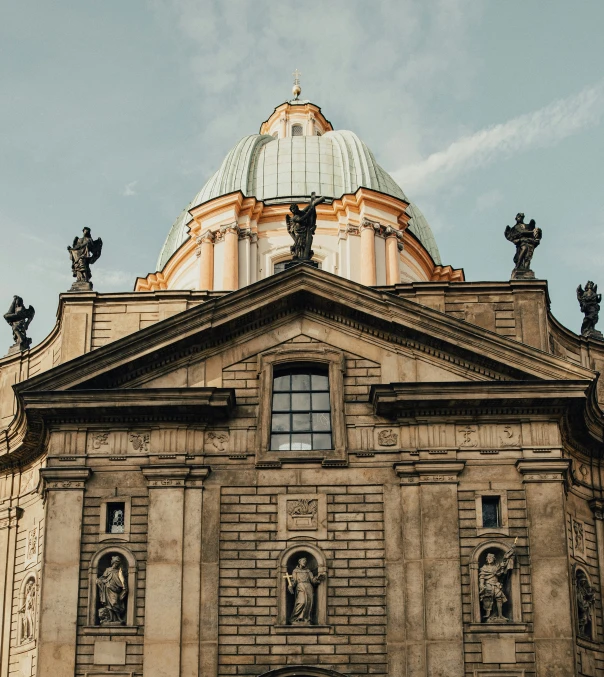 a tall church with a dome top with statues on it