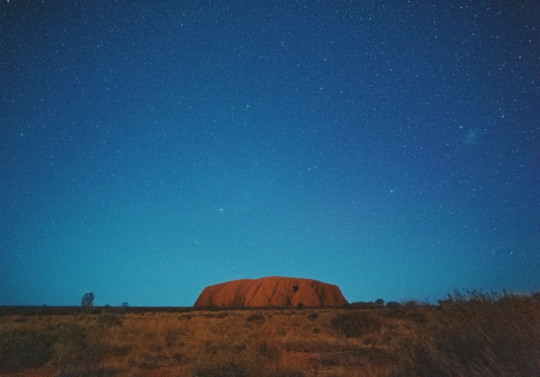 two large rocks in an empty plain with stars above them