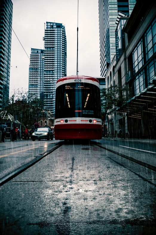 a passenger train drives down a rain soaked street