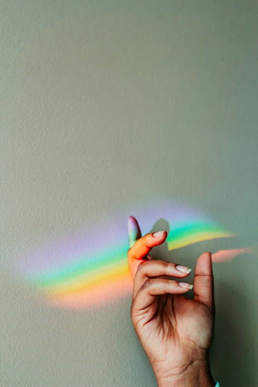 a person holding up a small rainbow shadow