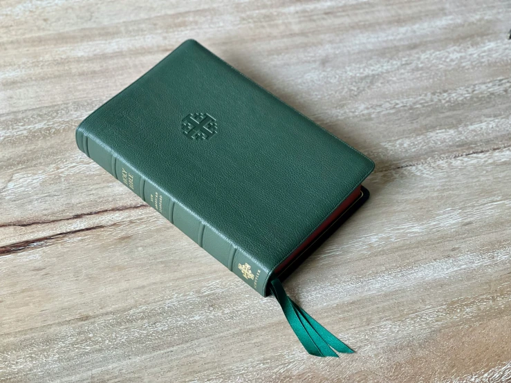 a bible sitting on a wooden surface covered in a green cloth