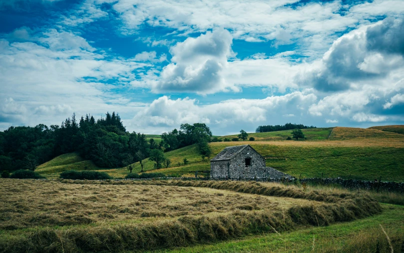 the old stone barn is near a very green meadow