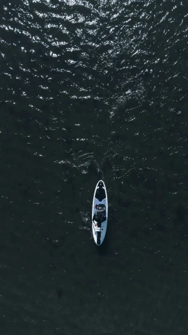 a boat with one rowboat at the bow floats through a body of water