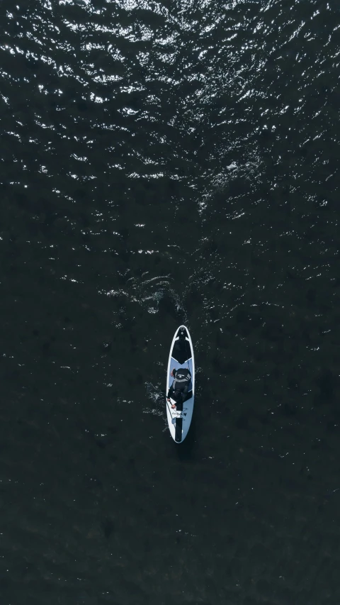 a boat with one rowboat at the bow floats through a body of water