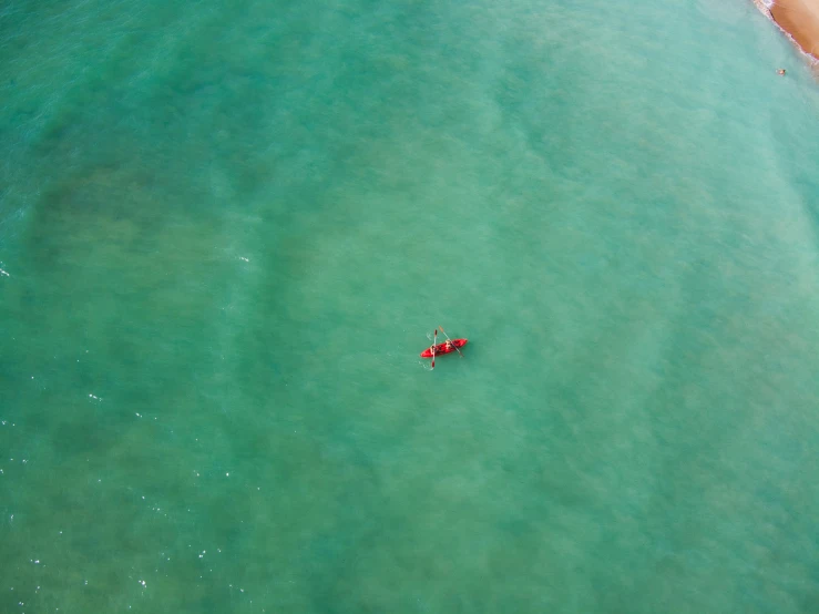 two people on a small red raft in the ocean
