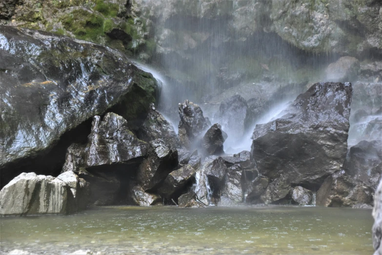 a small waterfall in a rocky field with water coming out of it