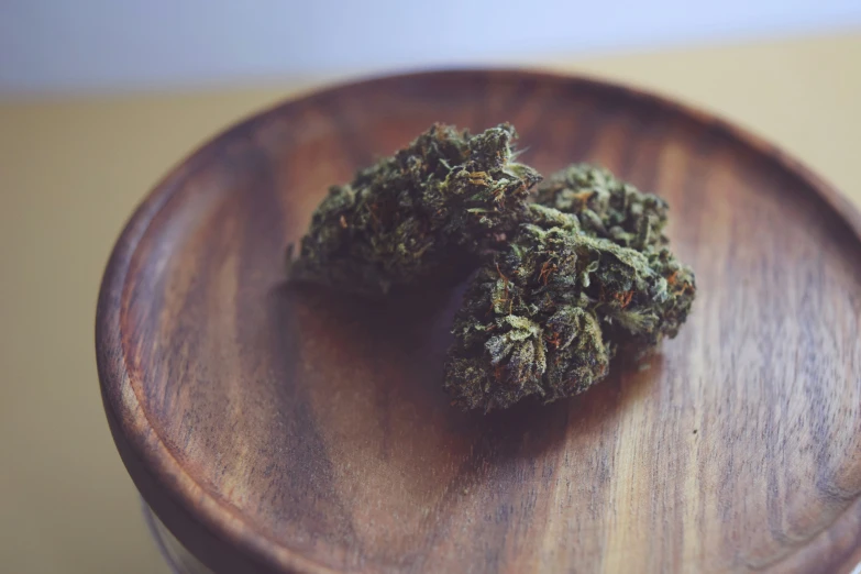 a close up of two pieces of marijuana on a wooden plate