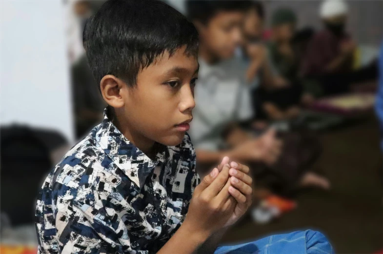 boy in shirt praying with other s around him