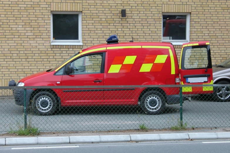 the red van is parked behind a fence