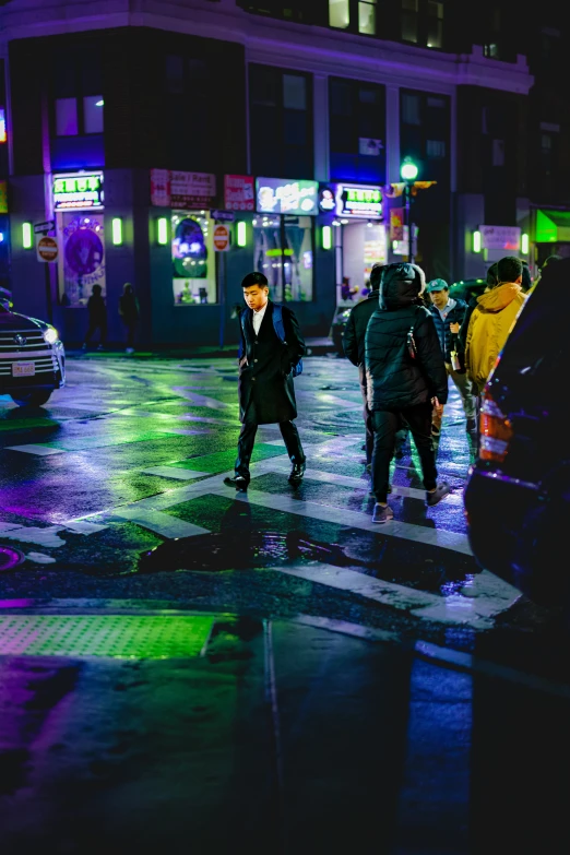 pedestrians waiting on a wet sidewalk as the rain starts to change colors