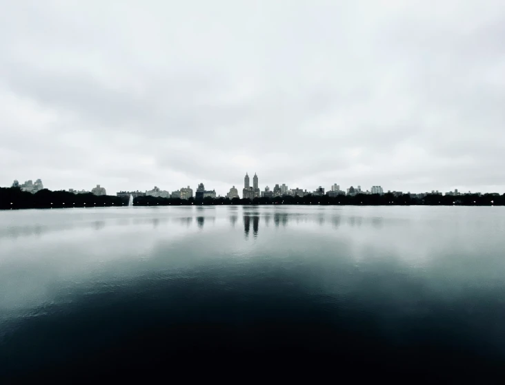 a lake surrounded by tall buildings with a clock tower in the distance