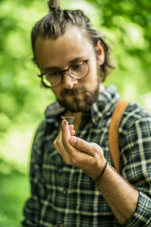 a man with a beard is holding out a small erfly