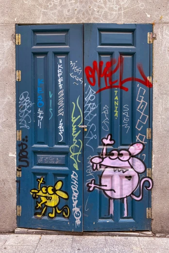 two doors covered in grafitti outside a building