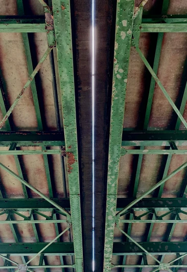 the underside of two green metal structure with rust spots