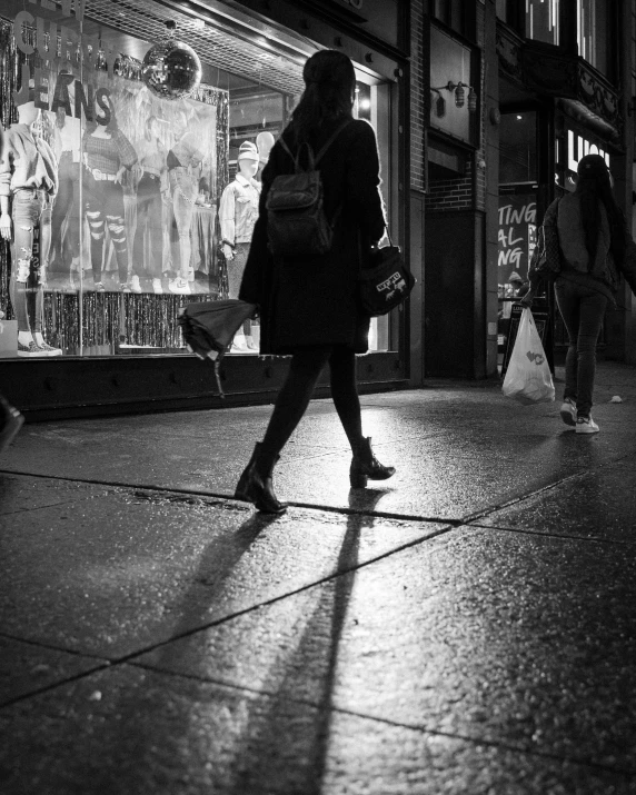 a woman is walking down the sidewalk at night