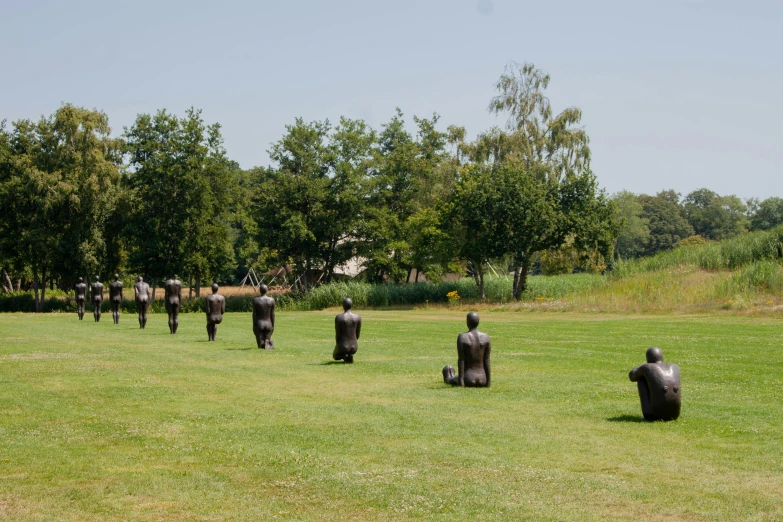 some sculptures sit on the grass near some trees