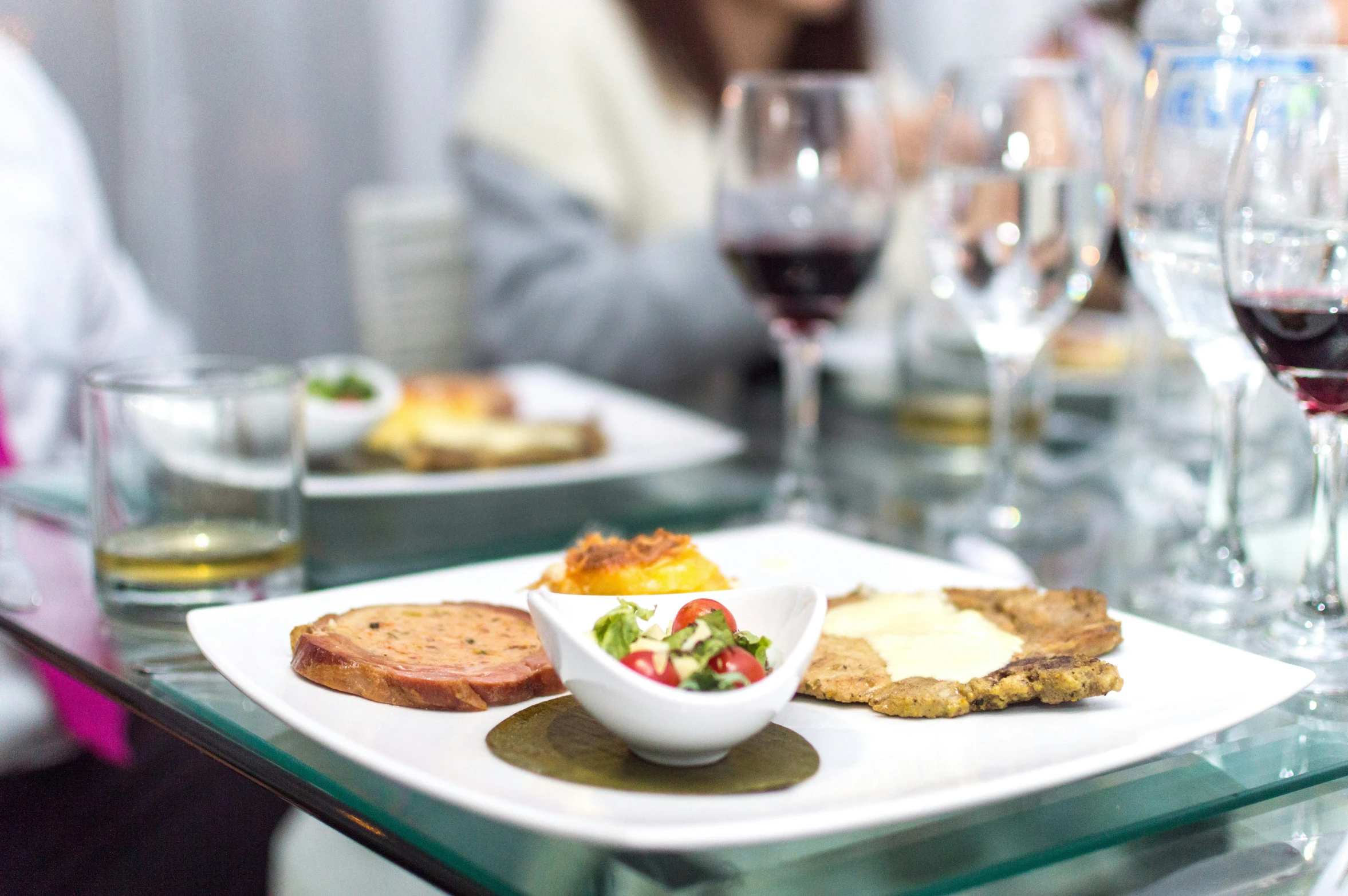 a couple of glasses of wine and some food on a glass table