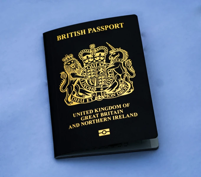 a british passport sitting on top of a blue surface