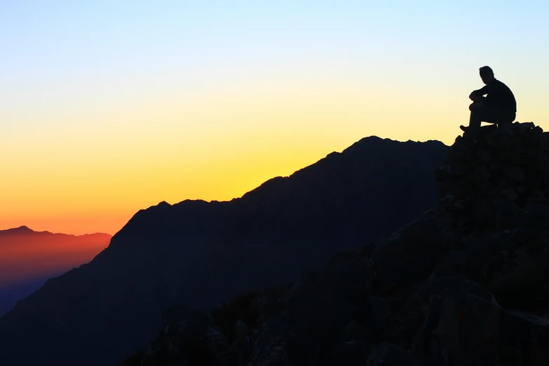 the man is sitting on the top of a mountain