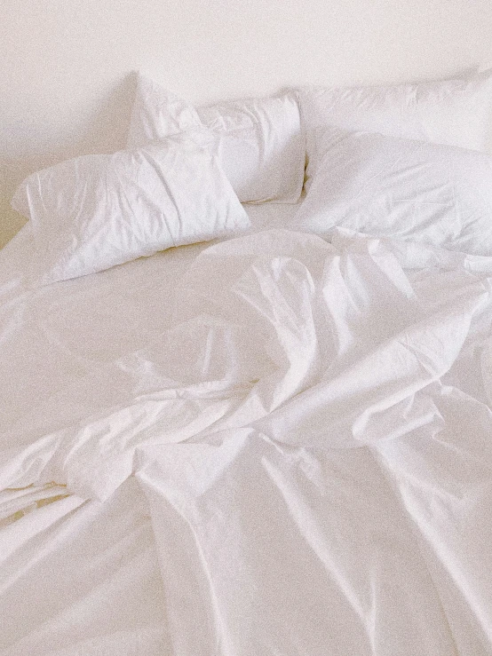 a bed with white sheets and pillows is not made