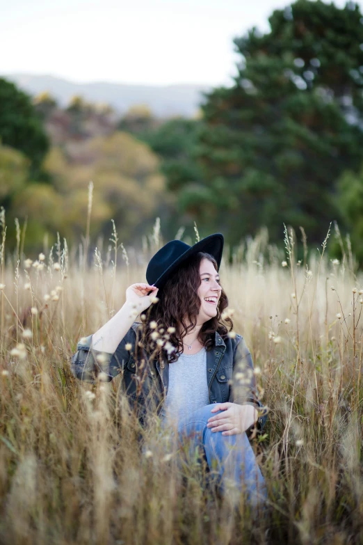 a woman in blue sitting on a field smiling