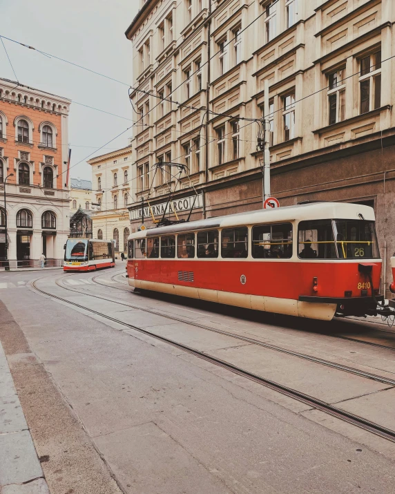 an empty street with trolleys and cars coming towards a building