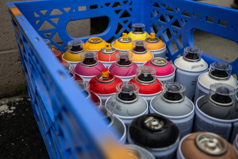 multiple colors of spray cans are packed in the bin