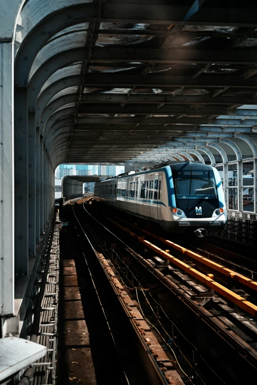 the commuter train is passing under the metal structure