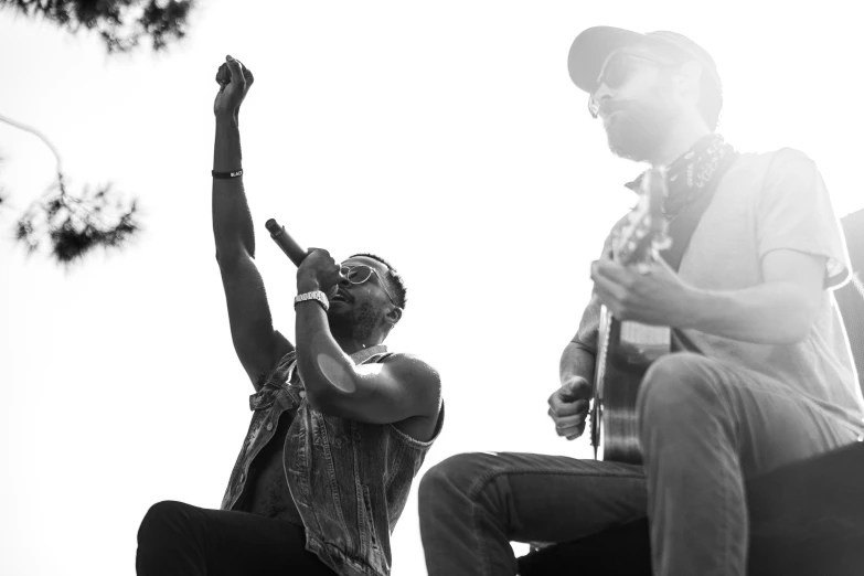 black and white po of a guitar player in mid air as another plays on the bass