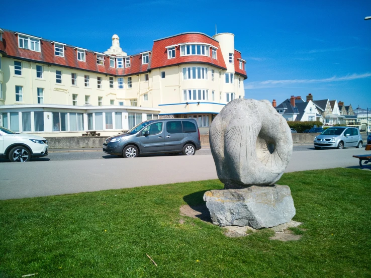 a large stone statue sits in front of an orange and white building