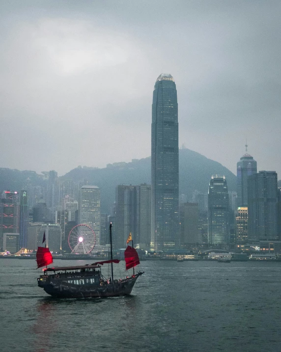 a small boat in the ocean in front of some very tall buildings