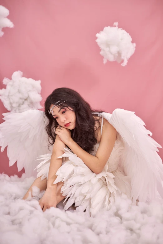 a beautiful young woman sitting on top of a cloud covered ground