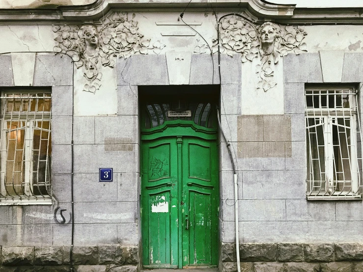 a green door is open by a building