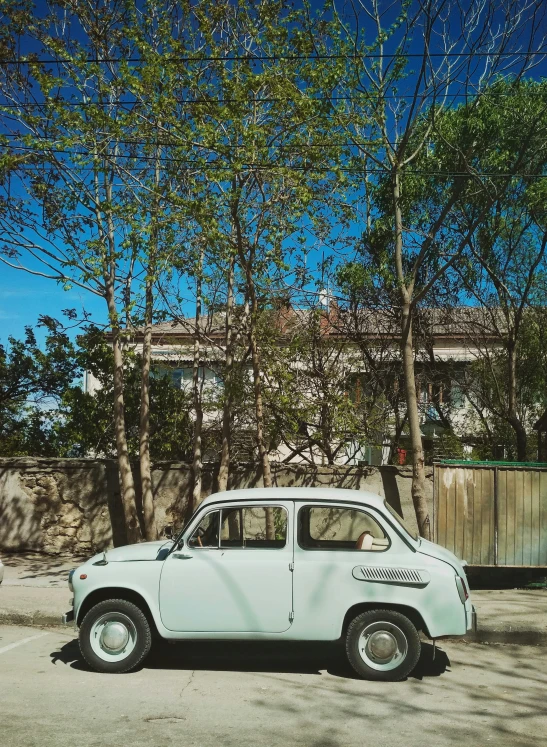 the old car is parked in the lot in front of the tree