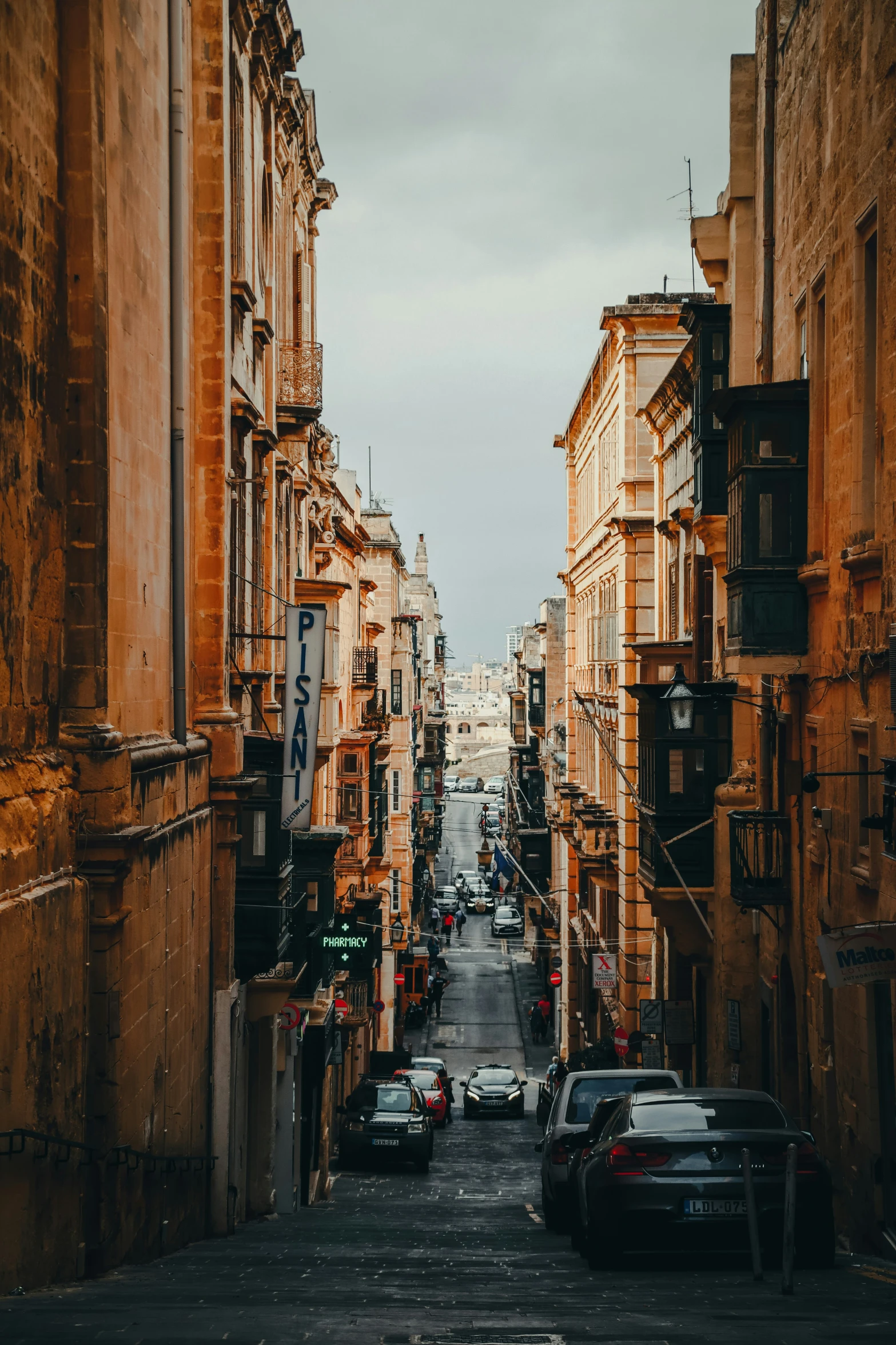 an alley between buildings and a street where cars are parked