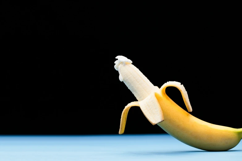 a yellow banana on a blue surface with the peel still attached