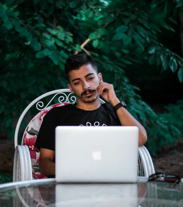 a man is on his laptop at the table and talking on the phone