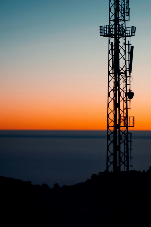 a phone tower stands in the middle of a silhouette